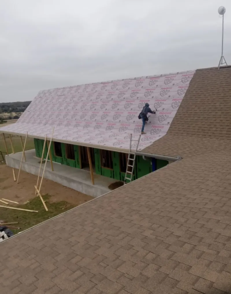 Worker preparing underlayment for a metal roof installation in Savage